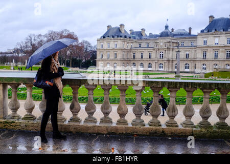 Ein schönes junges Mädchen genießt die Aussicht unter einem Dach an einem regnerischen Tag im Jardin du Luxembourg in Paris, Frankreich. Stockfoto