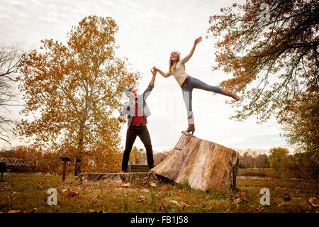 Junges Paar spielen auf Baum stump im Herbst park Stockfoto