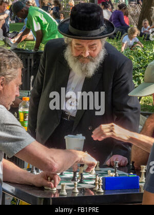 Ein orthodoxer Jude in schwarzen Hut und Vollbart kibitzes auf ein Freiluft-Schachspiel Spiel im New Yorker Stadtteil Washington Square, Greenwich Village. Stockfoto