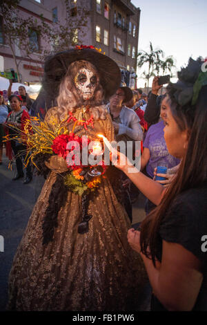 Kostümiert mit einem Skelett Gesicht, La Calavera Catrina ("Dapper Skelett") Leuchten Kerzen am Denkmal Altäre während der Tag der Toten oder Dia de Muertos Zeremonien unter Hispanics in Santa Ana, Kalifornien. Der Urlaub konzentriert sich auf Versammlungen von Familie und Freunden zu beten Stockfoto