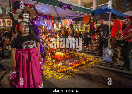 Ein Altar zu Ehren eines verstorbenen Familienmitglieds ist ausgestellt am mexikanischen Tag der Toten oder Dia des Muertos in einem hispanischen Viertel in Santa Ana, CA. Hinweis gestaltet Porträt des verstorbenen im Hintergrund, Mutter und Tochter von votive Kerzen beleuchtet, ich Stockfoto