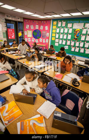 Hispanic Schüler der dritten Klasse geben Sie Informationen in ihren Google Chromebook Laptop-Computer in einem San Clemente, CA, Grundschule Klassenzimmer. Hinweis: Konzentration und schriftliche Aufsätze auf Pinnwand veröffentlicht. Stockfoto