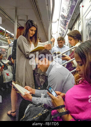 New York City u-Bahn-Fahrgäste lesen Bücher, wie sie reisen, während eine Frau im Vordergrund ein Handy liest. Stockfoto