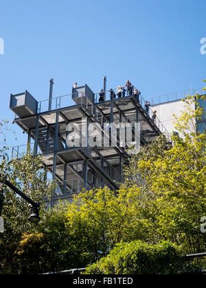 Umrahmt von Zierbäume, stehen Besucher, das Whitney Museum of Art im Meatpacking District der Lower West Side von Manhattan, New York City, auf das Museum auskragenden Balkon. Das Museum wurde vom Architekten Renzo Piano entworfen. Stockfoto