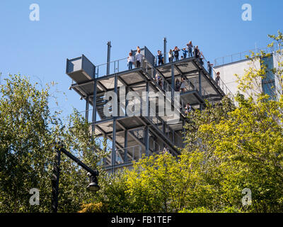 Umrahmt von Zierbäume, stehen Besucher, das Whitney Museum of Art im Meatpacking District der Lower West Side von Manhattan, New York City, auf das Museum auskragenden Balkon. Das Museum wurde vom Architekten Renzo Piano entworfen. Stockfoto