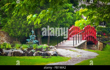 Kleine rote Fußgängerbrücke über Bach in einem Park in Perth Kanada ausgeführt. Stockfoto