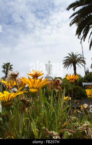 Statue der Jungfrau Maria auf San Cristobal Hügel, Santiago de Chile mit gelben Frühlingsblumen. Stockfoto