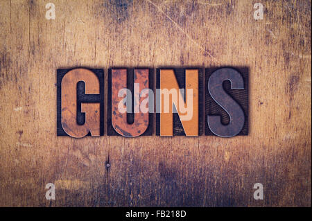 Das Wort "Guns" in schmutzigen Vintage Buchdruck Typ auf einem alten hölzernen Hintergrund geschrieben. Stockfoto