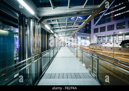 Fußgängerweg und modernen Wolkenkratzern in der Nacht, in Hong Kong, Hong Kong. Stockfoto