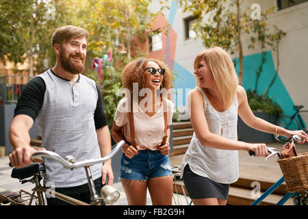 Gemischte raste Gruppe von Freunden in der Stadt pendeln. Drei junge Menschen gehen mit ihren Fahrrädern und Spaß haben. Stockfoto