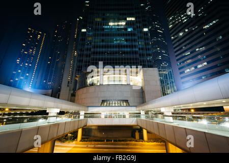 Moderne Wolkenkratzer und Fußgängerbrücken in der Nacht im Central, Hong Kong, Hong Kong. Stockfoto