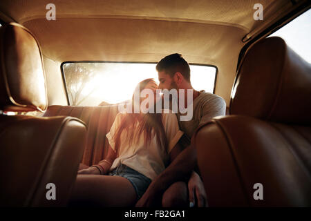 Romantische junges Paar auf Rücksitz des Autos. Liebespaar auf Roadtrip. Stockfoto