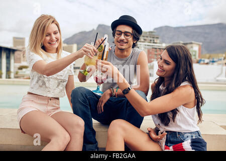 Glückliche junge Freunde Toasten Cocktails auf einer Party auf dem Dach. Junge Leute rumhängen und Getränke zu genießen. Stockfoto