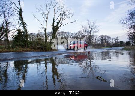 Ein Auto spritzt durch eine überschwemmte Straße nach Flusses Wharfe die Banken wieder in Ilkley, West Yorkshire, Großbritannien platzte. Stockfoto