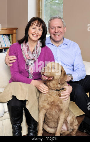 Ein paar mittleren Alters saß auf dem Sofa umarmt ihren Hund Stockfoto