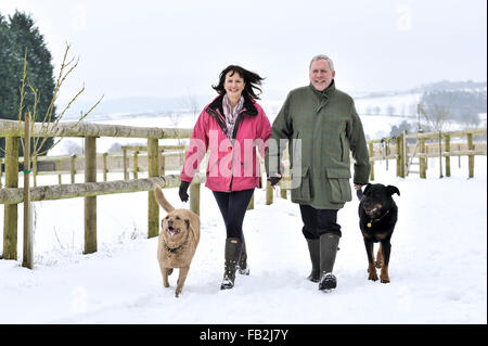 Applying paar Spaziergang mit ihrem Hund in eine Winterlandschaft Stockfoto