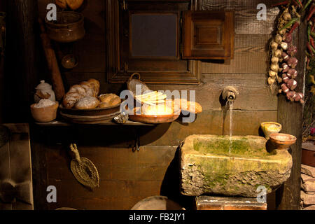 Alte Küche mit Broten und hängend, Knoblauch und Paprika-Streifen. Wir sehen auch einige Küchenutensilien und einen alten Brunnen. Stockfoto