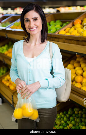 Porträt einer lächelnden Frau kaufen Orangen Stockfoto