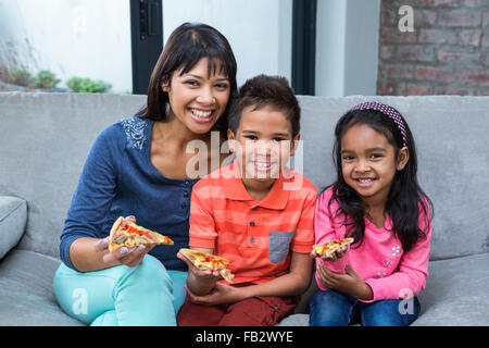 Glückliche Familie Essen Pizza auf dem sofa Stockfoto