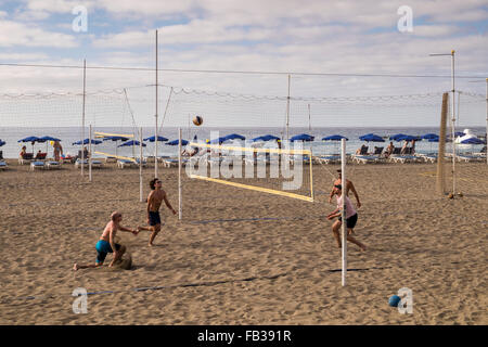 Gruppen von Jugendlichen spielen Beach-Volleyball am Strand Las Vistas in Los Cristianos, Teneriffa, Kanarische Inseln, Spanien. Stockfoto