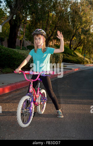 Ein Tween Mädchen Radfahrer signalisiert eine Rechtskurve mit ihrem linken Arm auf einer Straße in Lake Forest, CA-MODEL-RELEASE Stockfoto