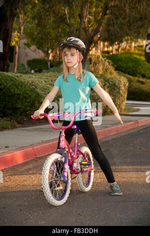 Ein Tween Mädchen Radfahrer signalisiert einen Anschlag mit ihrem linken Arm auf einer Straße in Lake Forest, CA. MODEL-RELEASE Stockfoto