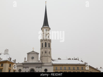 Die Außenseite des Teil des St.-Michaels Kirche in Wien im Winter mit Schnee auf Dächern. Der Hauptturm der Uhr zu sehen. Stockfoto