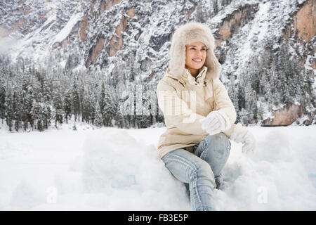 Magische Mischung aus Wintersaison und Berg Landschaft schaffen die perfekte Stimmung. Glückliche junge Frau im weißen Fell und Pelz Hut sitzen Stockfoto