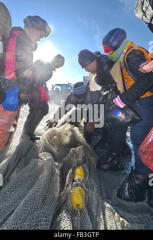 (160109)--SONGYUAN, 9. Januar 2016 (Xinhua)--Touristen versammeln, um Fische fangen auf dem Chagan-See in Songyuan City, Nordost-China Jilin Province, 8. Januar 2016 zu sehen. Chagan See, der zum traditionellen Winter Angeln, die bis in prähistorische Zeiten zurückreicht bekannt ist, ist der einzige Ort, der die älteste mongolische Fangmethode speichert. Während der jährlichen Winter Angeln stattfindende Festival ist um zu erinnern, die alte Winter Fischertradition, Fischer zunächst viele Bohrungen durch das dicke Eis und dann ein Netz unter dem Eis. Das Netz wird schließlich von einem Pferd-Zeichnung Winde herausgezogen. Das See-set Stockfoto