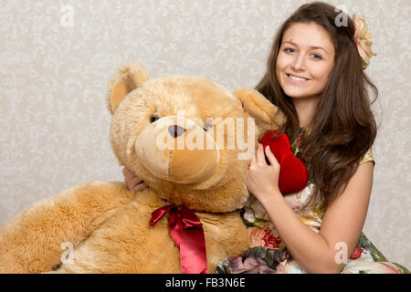 Lächelndes Mädchen hält gefüllte Herz und riesigen Bären Stockfoto