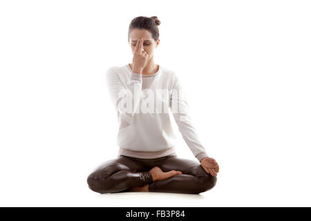 Yoga-Mädchen auf weißem Hintergrund üben Nadi Shodhana Pranayama (Stellvertreter, Nasenloch, atmen) in Lotus-pose Stockfoto