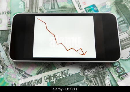 Telefon mit absteigender Diagramm auf dem Bildschirm auf die verstreuten Trümmern Banknoten Stockfoto