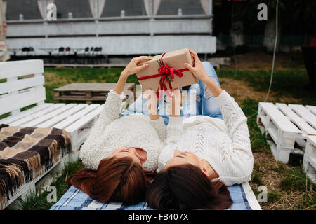 Mädchen liegen und packt ein Geschenk Stockfoto