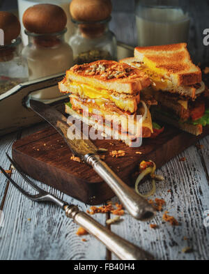 Sandwich mit Ei, Tomaten, Zwiebeln und Speck auf einem Vintage Holz-Hintergrund im rustikalen Stil. Abgeschwächt. Stockfoto