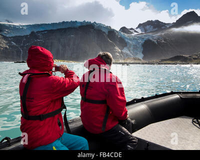 Süd-Georgien, Gold Harbour, paar in aufblasbaren Rib Boot, Blick auf Küste Gletscher über dem Meeresspiegel Stockfoto