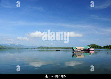 Hausboot schwimmt auf dem See über den Damm unter bewölktem Himmel in Thailand Stockfoto