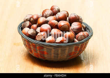 Haselnüsse (Corylus Avellana) in einem Korb auf hölzernen Hintergrund Stockfoto