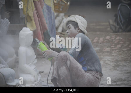 Bedeckt mit Marmorstaub, was dieser junge Mann einen Buddha aus Marmor mit und elektrische Bohrmaschine schnitzt. Der Staub wirbelte über alles. Stockfoto