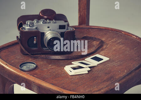 Retro-Kamera und alte Dias lagen auf einem Stuhl. Vintage-look Stockfoto