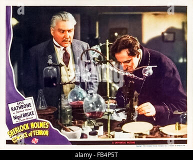 Lobby card für 'Sherlock Holmes und die Stimme des Terrors" 1942 mit Sherlock Holmes in seinem Labor. Unter der Regie von Roy William Neill mit Basil Rathbone (Holmes) und Nigel Bruce (Watson) und Evelyn Ankers (Kitty). Siehe Beschreibung für weitere Informationen. Stockfoto