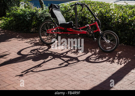 Eine rote Liegerad wirft einen langen Schatten auf die Ziegel Bürgersteig beim Parken auf der State Street in Santa Barbara, Kalifornien. Stockfoto