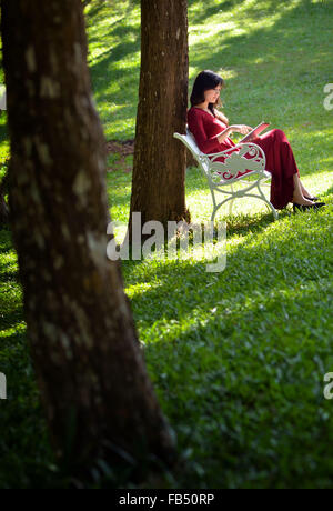 hübsche Frau mit Tablet im Garten Stockfoto