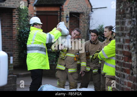 Feuerwehrleute heben und bewegen Sandsäcke, um zu verhindern, dass Häuser aufgrund eines geplatzten Flusses in Arundel, West Sussex, England, überschwemmt werden. Stockfoto