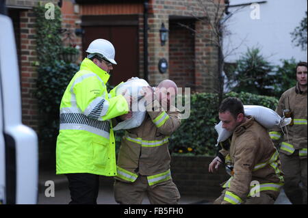 Feuerwehrleute heben und bewegen Sandsäcke, um zu verhindern, dass Häuser aufgrund eines geplatzten Flusses in Arundel, West Sussex, England, überschwemmt werden. Stockfoto