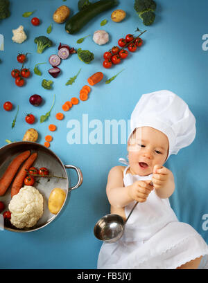 Baby Boy in Koch Hut mit Kochen Pfanne und Gemüse Stockfoto