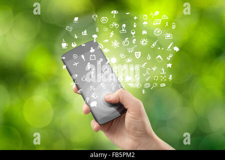Hand mit Smartphone mit gezeichneten Symbole auf grünen natürlichen Hintergrund Stockfoto