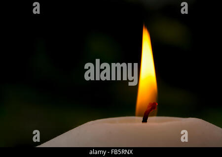 Nahaufnahme einer Kerzenflamme mit dunklem Hintergrund. Stockfoto