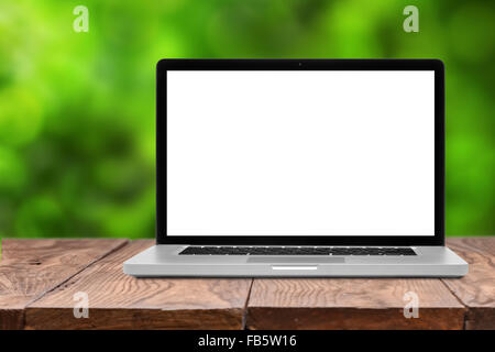 Laptop mit leeren Bildschirm auf leeren braunen Holztisch auf grünen natürlichen Sommer Hintergrund unscharf Stockfoto