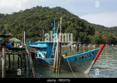 Altes Fischerboot gefesselt neben einem alten Anlegestelle in Teluk Bahang in Penang, Malaysia. Grünen Hügeln des Nationalparks hinter. Stockfoto