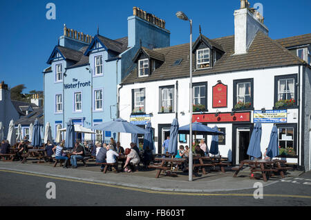 Menschen, die Getränke in der Sonne draußen The Waterfront Hotel und The Crown Hotel in Portpatrick genießen. Stockfoto